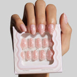 Model holding Angel Glaze Dot press-on nails in extra short almond shape with white polka dot design