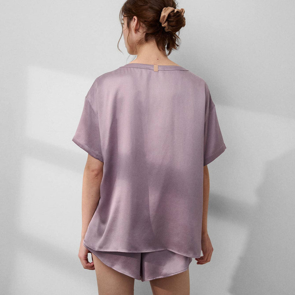Woman wearing mauve LUNYA washable silk tee and shorts set, back view on neutral background