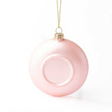 Pink glass ornament with gold cap and string on white background