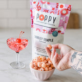 Shirley Temple popcorn in bowl with cocktail and product packaging by POPPY