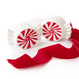 Red and white peppermint-striped ceramic salt and pepper shakers with red ribbon on white background