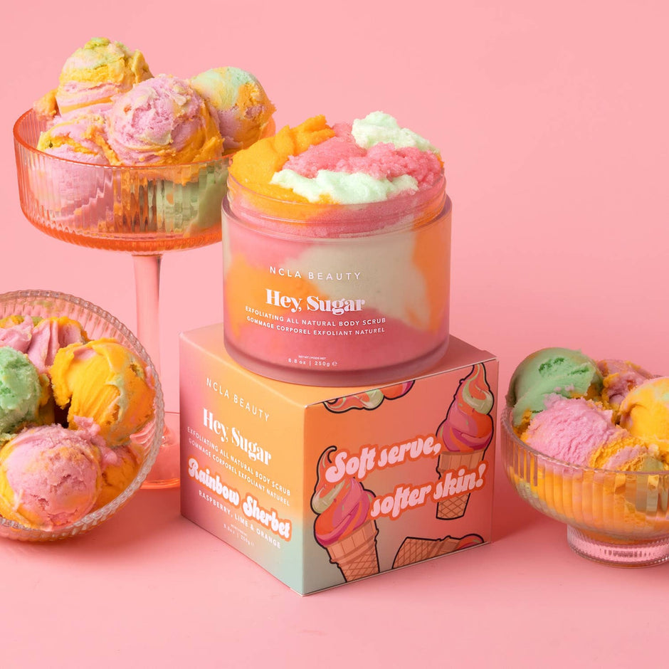 NCLA Beauty Hey Sugar body scrub surrounded by colorful ice cream and cupcake props on pink background