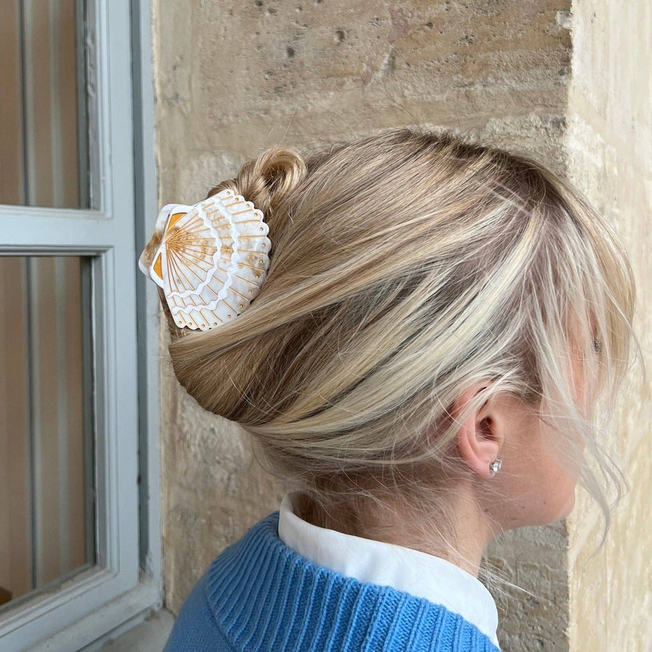 Solar Eclipse hand-painted seashell claw hair clip worn in blonde hair bun with blue sweater