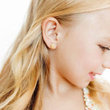 Gold shell stud earrings worn by a young girl with blonde hair, profile view