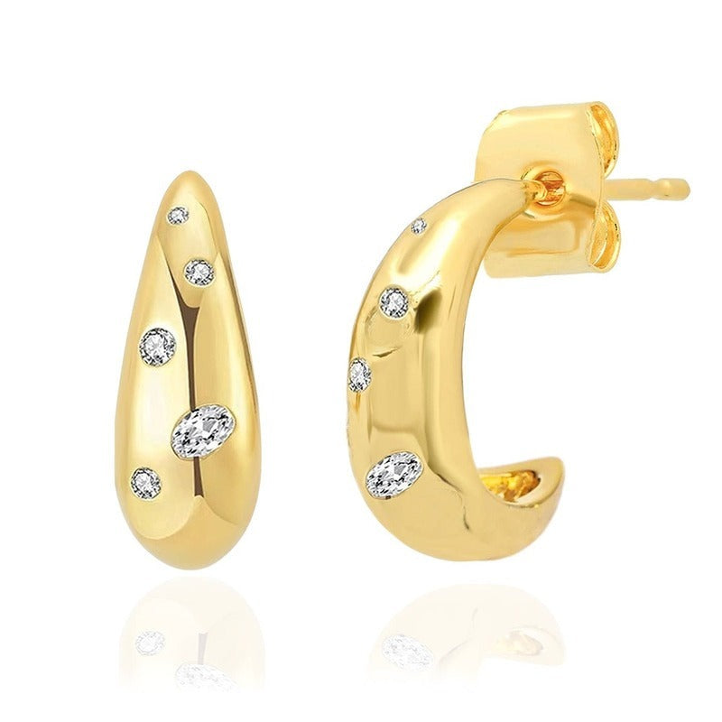 Gold teardrop huggie earrings with diamond constellation design on white background