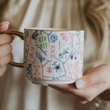 Mahjong Tiles Coffee Mug held in hands with striped fabric background