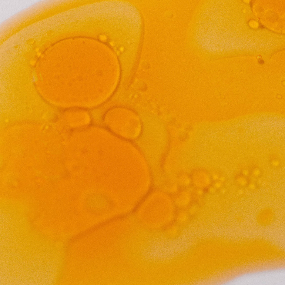 Vitamin C Elixir serum texture showing golden-yellow liquid with oil droplets
