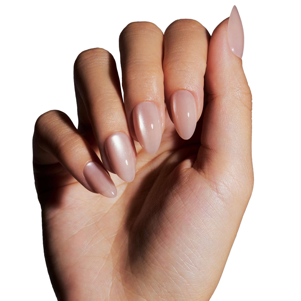 Woman wearing nude pink almond-shaped press-on nails with glossy finish against white background