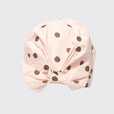 Blush pink shower cap with brown polka dot pattern on neutral background