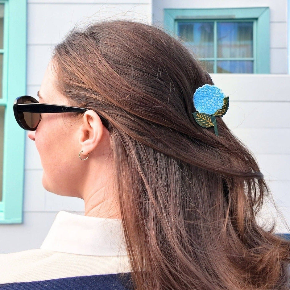 Blue hand-painted hydrangea claw hair clip worn in long brown hair outdoors