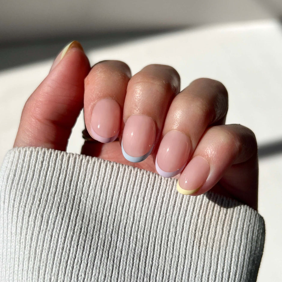 Close-up of a hand with neatly manicured nails holding a light gray sleeve.
