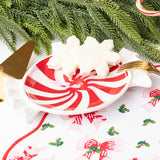 Red and white peppermint striped dessert plate styled with evergreen garland, gold fork, and festive holiday decorations