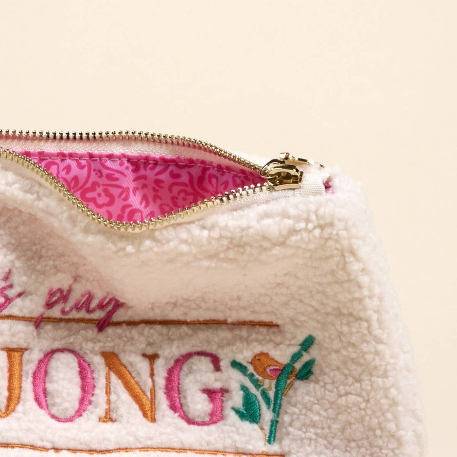 Cream teddy pouch with pink mahjong embroidery, gold zipper detail on neutral background