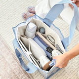 Person holding open a blue and cream tote organizer filled with various items on a textured surface