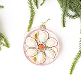 Pink glittered oyster platter ornament with evergreen branches on white background