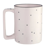 White ceramic mug with black star pattern and dark rim, featuring curved handle