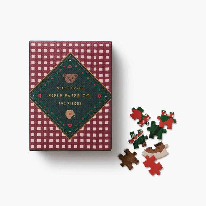 Rifle Paper Co. Beary Christmas 100-piece mini jigsaw puzzle box with colorful puzzle pieces displayed.