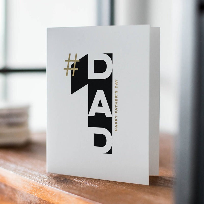 #1 Dad gold foil Father's Day card displayed on wooden surface near window