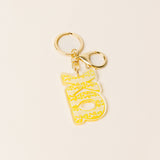 Yellow and white acrylic sorority letter keychain with gold-tone hardware and dual key rings