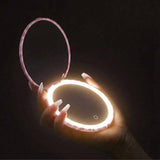 Blush zebra compact mirror with LED light held in hand against dark background