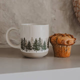 Forest Stoneware Coffee Mug with tree design displayed next to a muffin