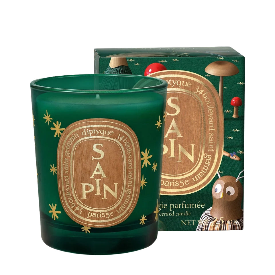 Diptyque Sapin small candle in green glass with gold stars beside its green holiday gift box