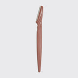 Brown dermaplaner tool on a light gray background