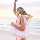 Pink bow jelly tote bag held by woman at beach during sunset