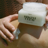 Person applying 'Bikini Club' body scrub to their skin
