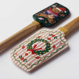 Two wooden spatulas with holiday designs on white background: one with teddy bear and one with wreath