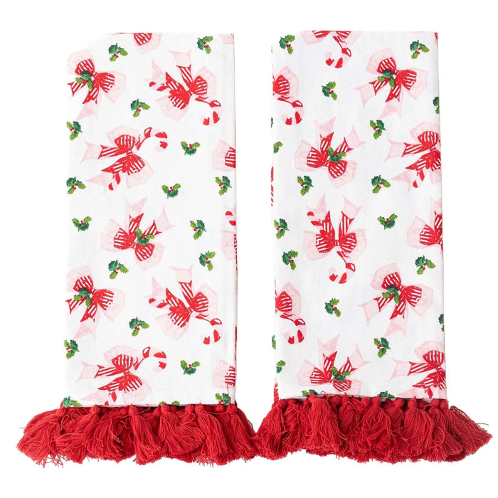 Set of two white kitchen towels with red bows, green holly, and red tassel trim on white background.
