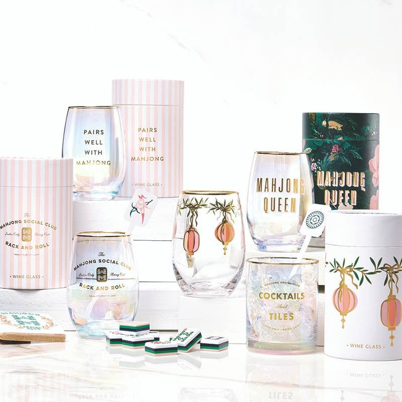 Gold foil mahjong-themed stemless wine glasses displayed in styled collection with coordinating home decor