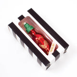 Red hot sauce bottle ornament with green glitter tree top in black and white striped gift box