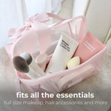 Pink bow cosmetic bag filled with makeup and accessories with text overlay stating 'fits all the essentials'