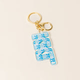 Blue floral acrylic letter keychain with gold keyring on neutral background
