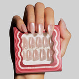 Model holding Celebritips press-on nails in short almond shape with pink pearl finish in packaging
