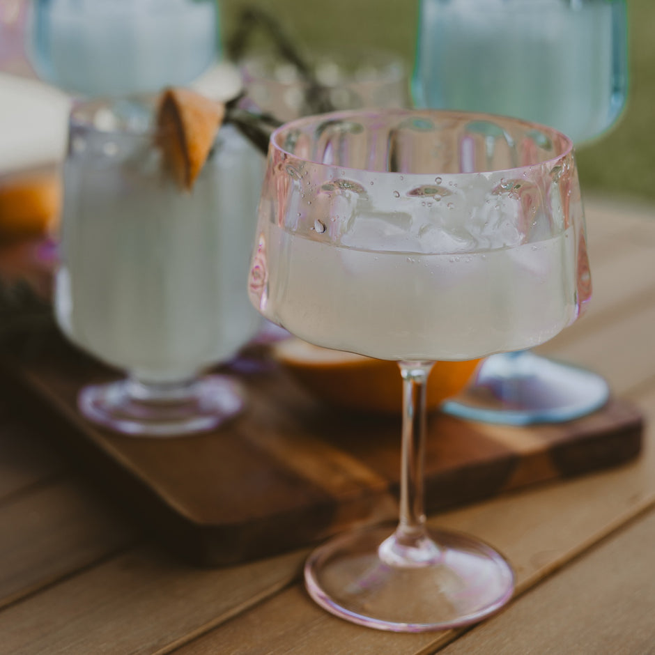 Outdoor plastic coupe glasses with ice water on wooden table in garden setting