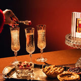 Hand dropping a cube into a champagne flute beside a tray of mini pies