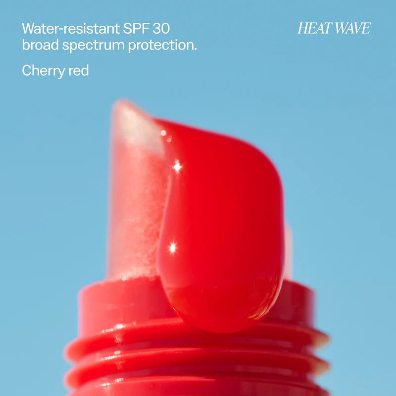 Red lip balm with cherry red color on a blue background, labeled 'HEAT WAVE'.