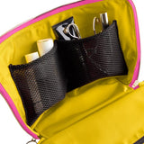 KUSSHI | Vacationer Makeup Bag — Flamingo Pink/Sunshine Yellow, Open makeup bag with bright yellow interior, pink zipper trim, and black mesh organizer pockets holding cosmetic tubes and a pair of scissors.