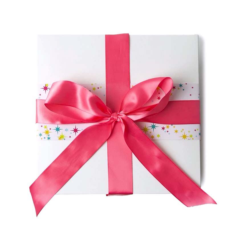 Gift box with a colorful star pattern on a blush sleeve and a glamorous pink satin bow